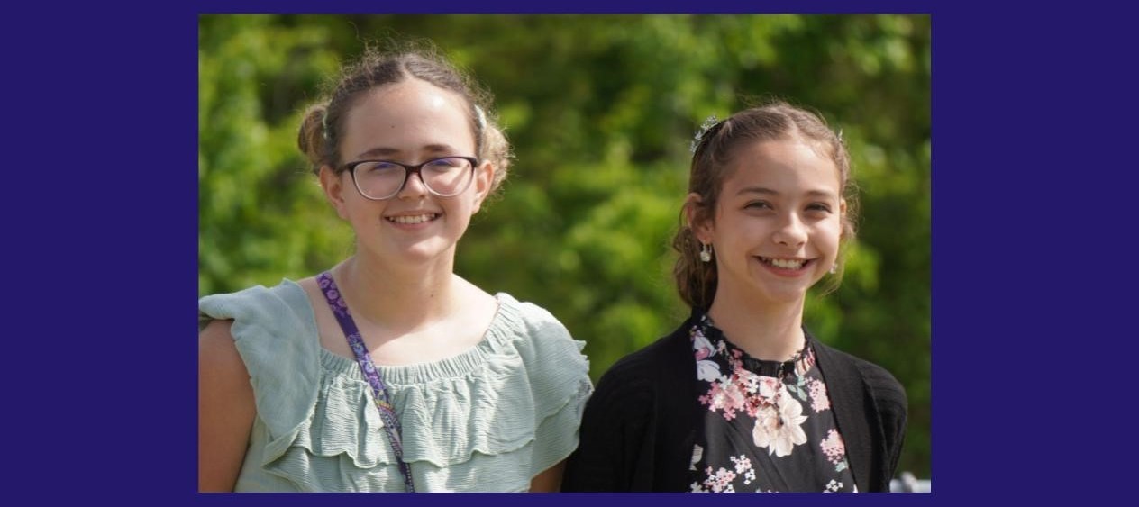 two girls smile outside